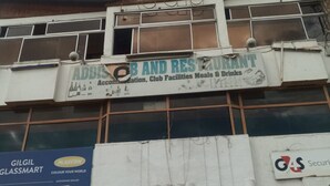 A building with multiple signs, including one for 'Addis OB and Resturant' offering accommodation, club facilities, meals, and drinks. - Addis Lodge (Gilgil)