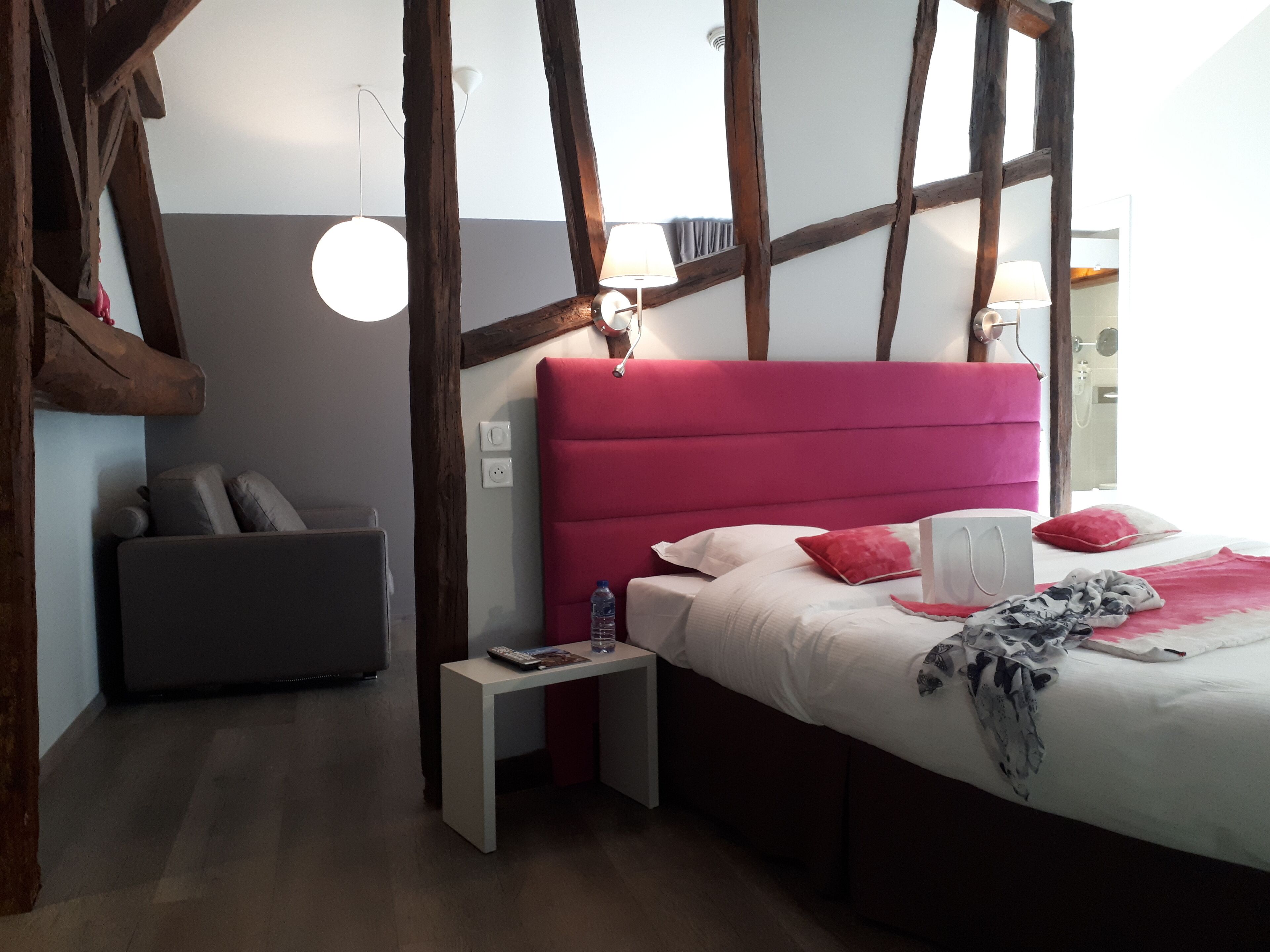 Un dormitorio con cama, mesita de noche y un pequeño sofá.