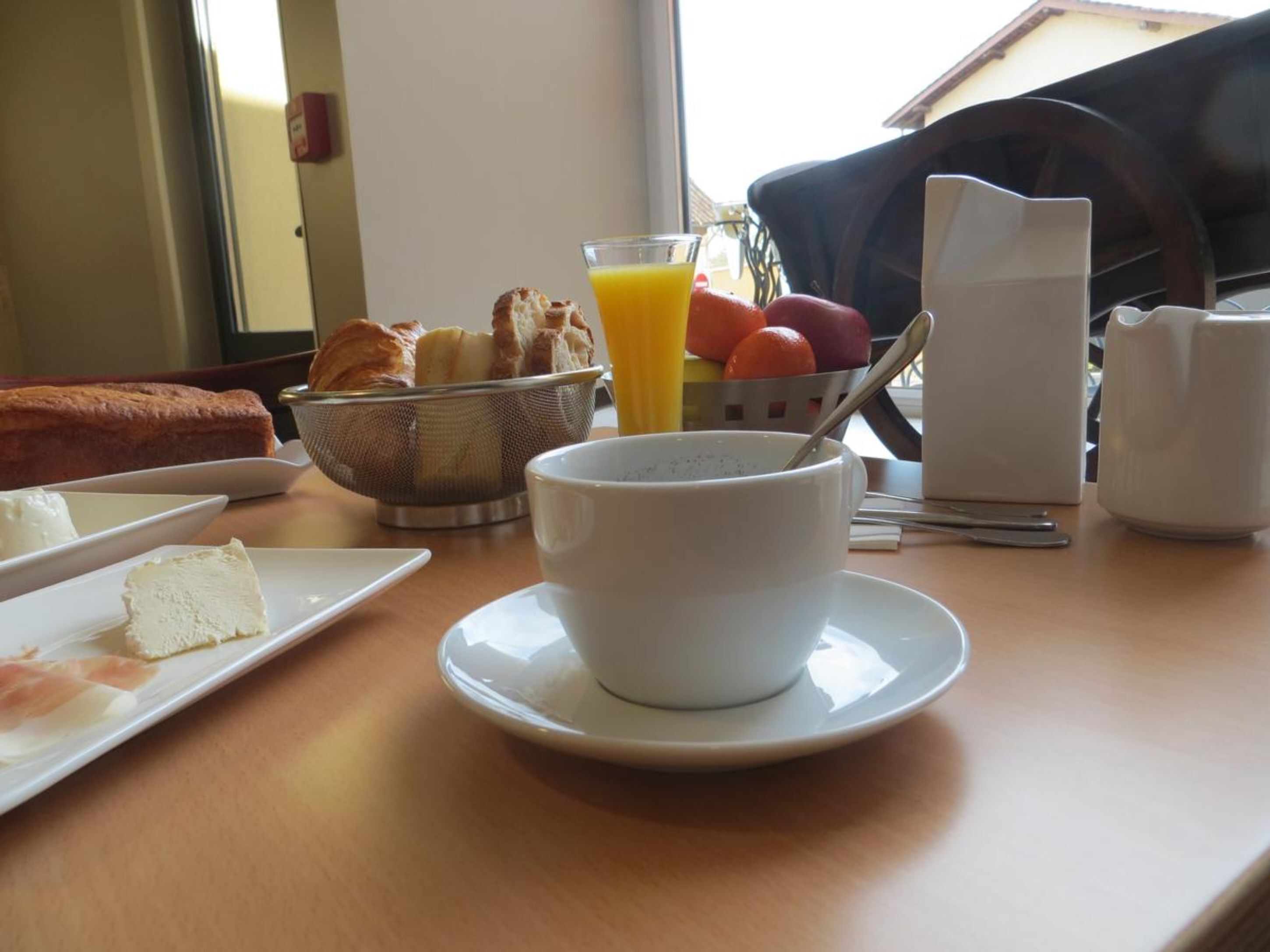 A breakfast table with croissants, orange juice, and a bowl of cereal.