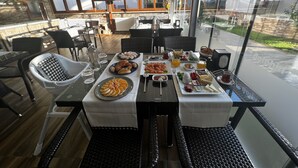 Un comedor con una mesa dispuesta para el desayuno, que incluye bollería, frutas y bebidas.
