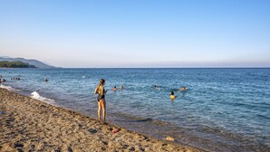 A beach with clear water, people swimming and standing on the shore. - Rose Resort Hotel (Kemer)