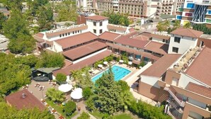 An aerial view of a hotel with multiple buildings, a swimming pool, and surrounding greenery. - Rose Resort Hotel (Kemer)