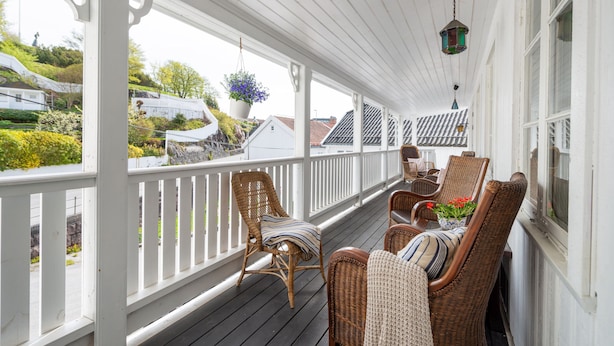 A covered porch with wicker furniture and hanging flower baskets. - Ibsens B&B (Grimstad)