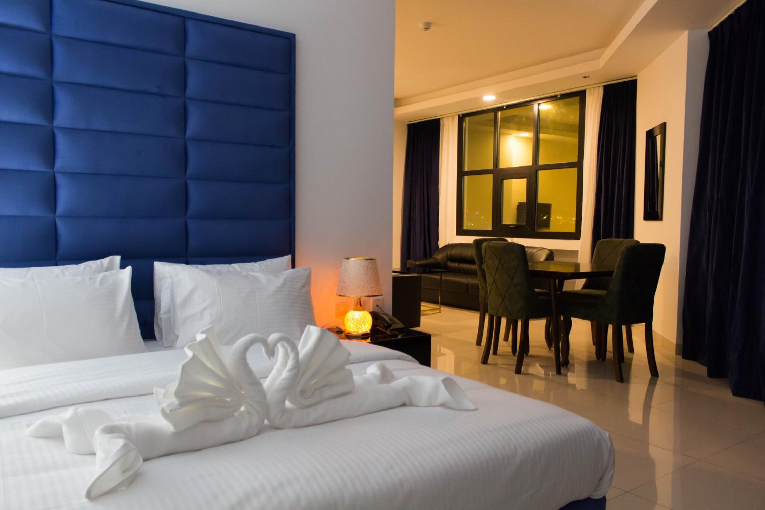 A hotel room with a large bed, a desk, and a dining area.