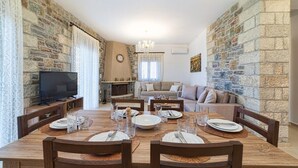 Un coin repas avec un mur en pierre, un téléviseur et un canapé à l’arrière-plan.