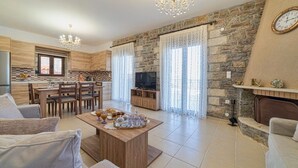 Un vaste espace de vie comprenant une table basse en bois, des canapés, un téléviseur et un mur en pierre.