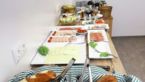 A buffet table with various food items, including bread, meats, and vegetables. - Hotel Garni Fischerfleck (Ismaning)
