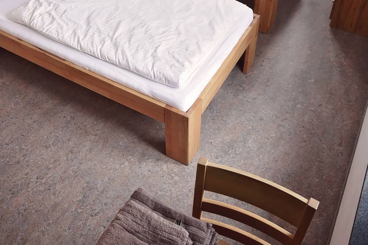 A room with two wooden beds, a table, and a chair.