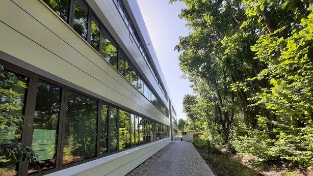 A modern building with large windows and a paved walkway. - Hotel Garni Fischerfleck (Ismaning)
