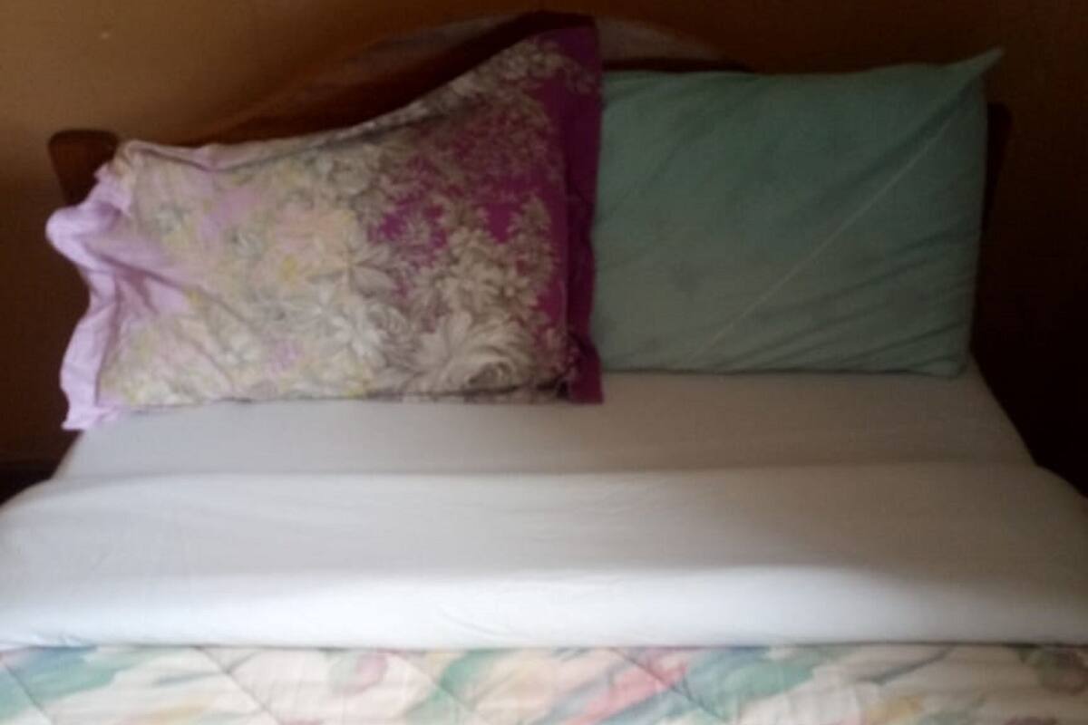 Una cama con un edredón floral, un cojín morado y un cojín verde.