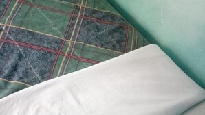 A bed with a white pillow and a green blanket. - Benliza Guest House - Adults Only (Gilgil)