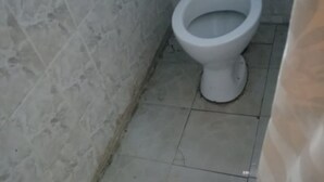 A small, tiled bathroom with a white toilet and a visible pipe on the wall. - Benliza Guest House - Adults Only (Gilgil)