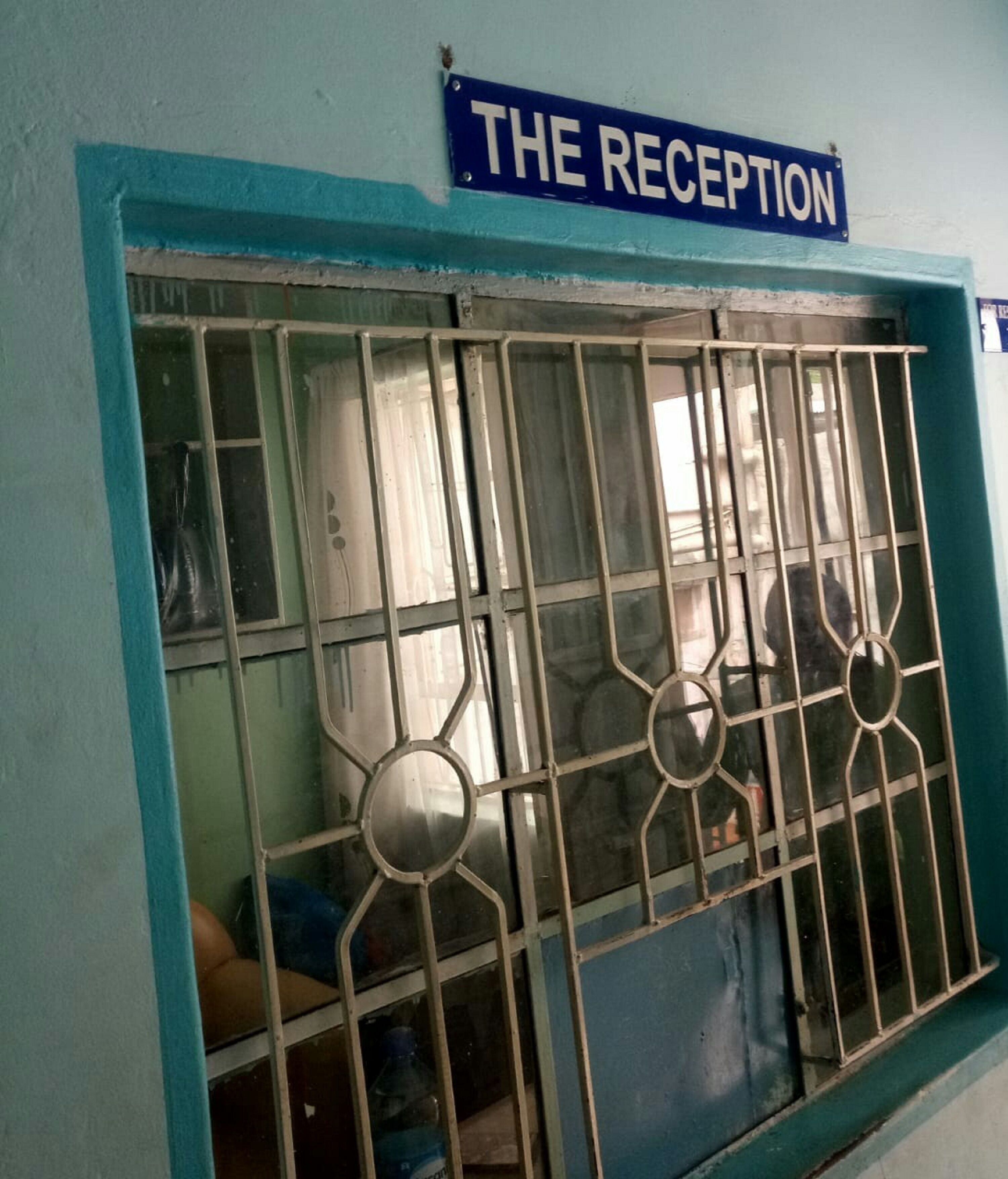 Uma área de recepção com uma placa que diz "THE RECEPTION" acima de uma janela com grades.