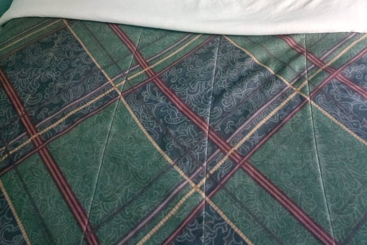A bed with a patterned bedspread, a pillow, and a headboard.