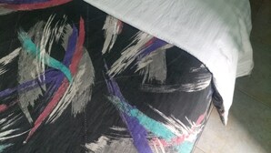 A bed with a white sheet and pillow, a black and colorful blanket, and a wooden headboard. - Benliza Guest House - Adults Only (Gilgil)