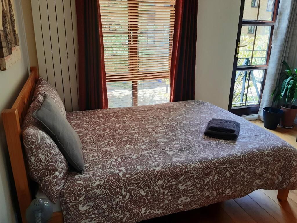 Una cama con una colcha estampada, una almohada y una manta sobre un piso de madera.