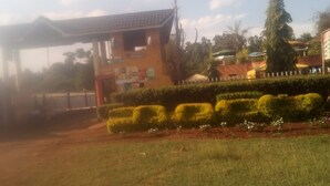 A building with a sign that reads "TUSKER" and a fenced area with neatly trimmed bushes. - Sun Citi Resort (Sagana)
