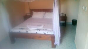 A single bed with a canopy, a nightstand, and a trash bin in a room with patterned flooring. - Sun Citi Resort (Sagana)