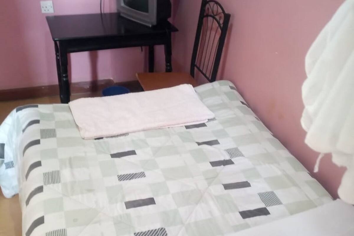 A bedroom with a bed, a television on a desk, and a chair.