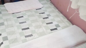 Ein Einzelbett mit karierter Bettdecke und gefaltetem Überwurf.