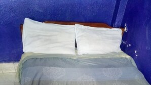 A bed with a striped bedspread and two pillows. - Chawaka Guest House (Gilgil)