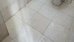 A small, tiled bathroom with a toilet and a wall-mounted tank. - Chawaka Guest House (Gilgil)
