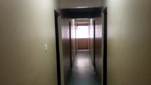 A long, narrow hallway with a tiled floor and beige walls. - Chawaka Guest House (Gilgil)