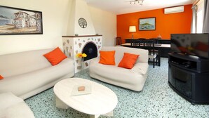 A living room with a fireplace, a dining area, and a TV. - Stunning private villa for 6 guests with A/C, private pool, WIFI, TV, terrace and pets allowed (Calpe)