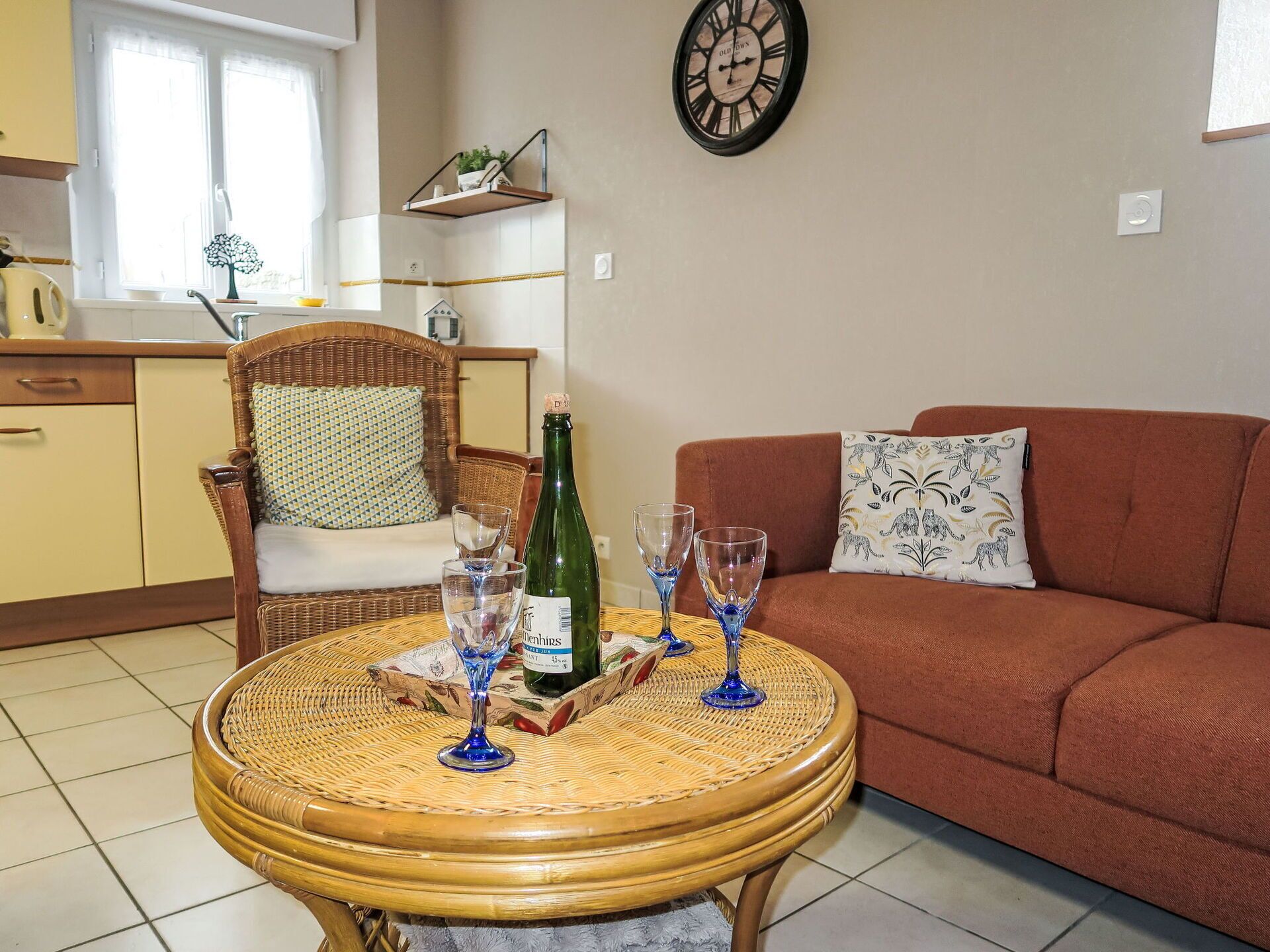 A living room with a round wooden table, a brown sofa, and a wicker chair.