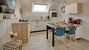 A modern kitchen with a dining area, featuring a built-in microwave, a sink, and a dining table with chairs.