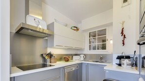 A modern kitchen with grey cabinets, stainless steel appliances, and a window with a view. - Lovely apartment for 6 guests with WIFI, A/C, TV, terrace and panoramic view (Grimaud)
