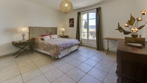 A bedroom with a bed, bedside tables, a hanging light fixture, a window with curtains, and a view of the outdoors. - Lovely apartment for 6 guests with WIFI, A/C, TV, terrace and panoramic view (Grimaud)