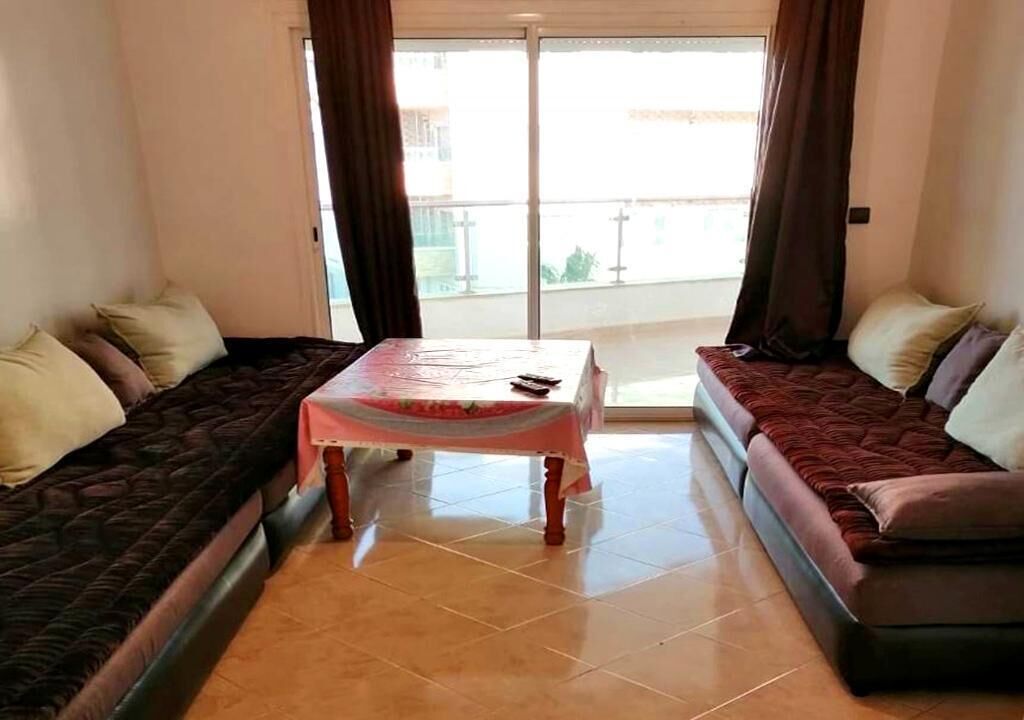 A living room with two sofas, a small table, and a view through a glass door.