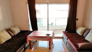 A living room with two sofas, a small table, and a view through a glass door. - Residence Yasmine Mdiq 4692 (Mdiq)