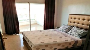 A bedroom with a bed, curtains, and a view to the outside. - Residence Yasmine Mdiq 4692 (Mdiq)