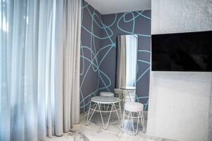 Un bagno moderno con pavimento in marmo, uno specchio grande e una parete con graffiti blu astratti.