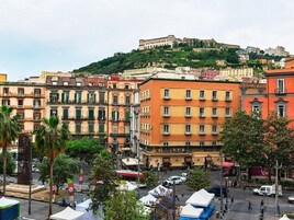 Paesaggio urbano con edifici storici e una fortezza in cima a una collina.