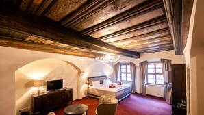A hotel room with a wooden ceiling, a bed, a TV, a desk, and a chair. - Pension Donatus (Pirna)
