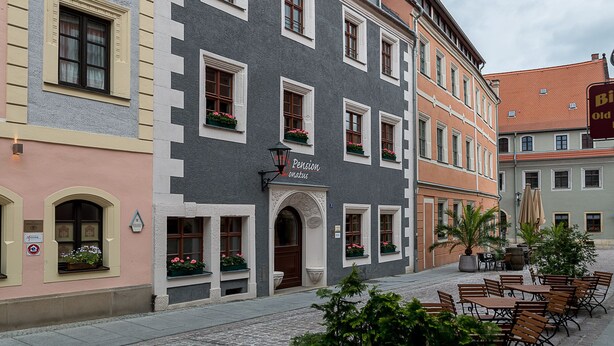 A multi-story building with a ground-floor café area featuring outdoor seating. - Pension Donatus (Pirna)