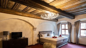 A hotel room with a wooden ceiling, a bed, a TV, a desk, and a chair. - Pension Donatus (Pirna)