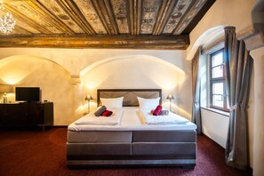A hotel room with a large bed, a TV, and a desk with a lamp. - Pension Donatus (Pirna)