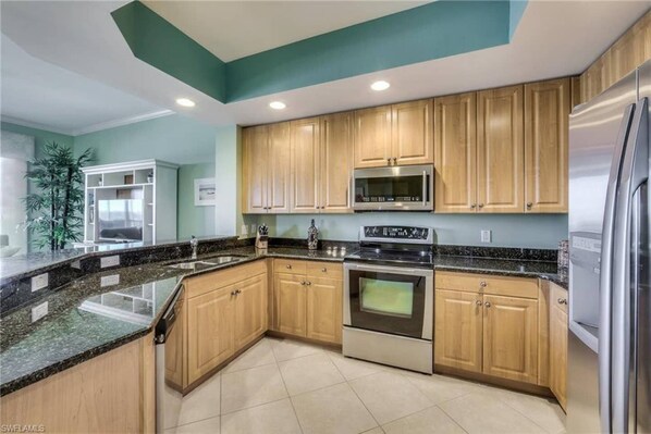 A modern kitchen with wooden cabinets, a stainless steel refrigerator, a microwave, and a stove.