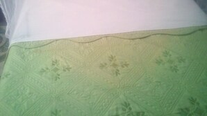 Una cama con un colchón blanco y una colcha verde.