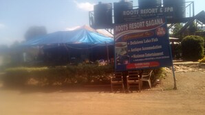 Letrero de Roots Resort & Spa en Karibu Sanga, destacando atractivos como sabroso pescado del lago, alojamiento rústico y entretenimiento sin igual.
