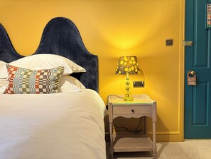 A bed with a headboard, a bedside lamp, a nightstand, and a door with a do not disturb sign. - East Beach Guest House (Littlehampton)