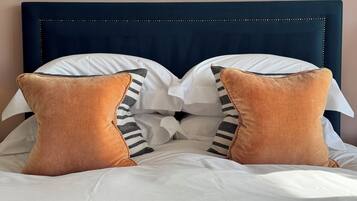 A bed with a dark headboard, white bedding, and two brown pillows with black stripes.
