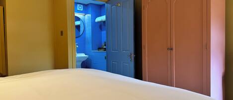 A hotel room with a bed, a wardrobe, and a bathroom visible through an open door.