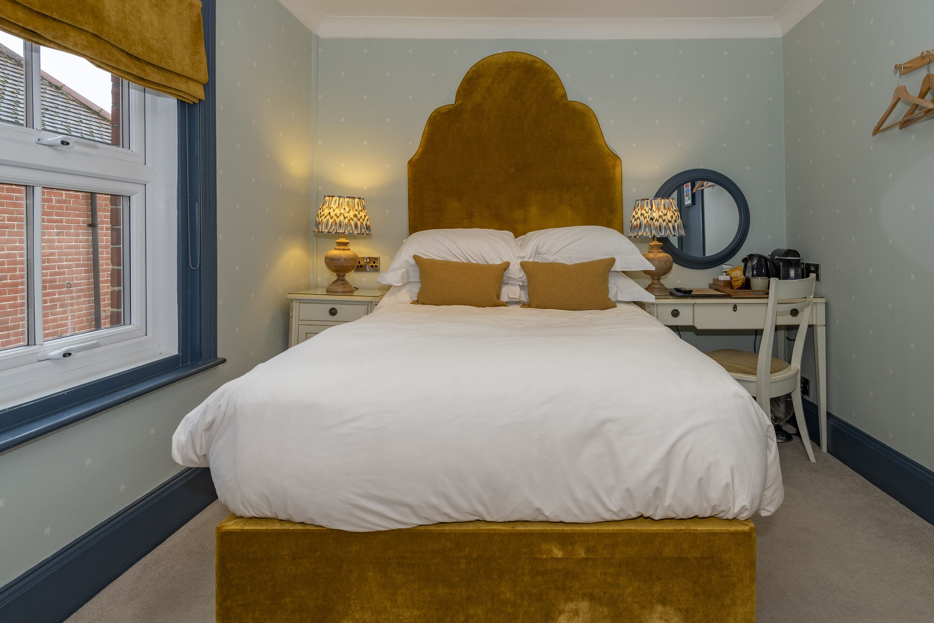 A bedroom with a bed, bedside tables, a chair, a mirror, and a window.