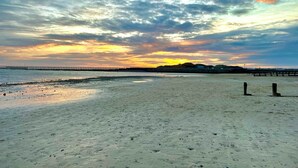 A beach with a pier extending into the water, sandy shore, and a sunset in the background. - East Beach Guest House (Littlehampton)