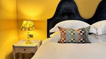 A hotel room with a bed, a nightstand, a lamp, and a checkered pillow.